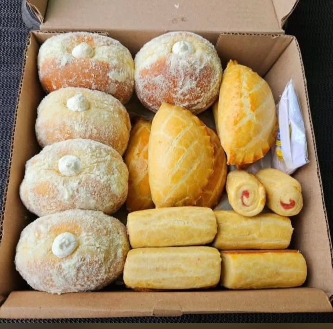 Box of cream doughnuts, meat pies, sausage rolls and jam rolls by Dauntless Delight