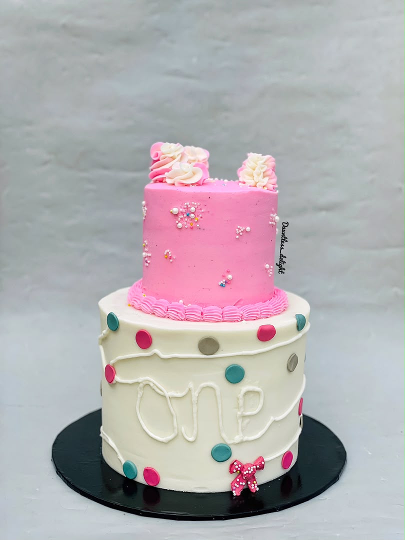 Two tier polka dot first birthday cake in white and pink