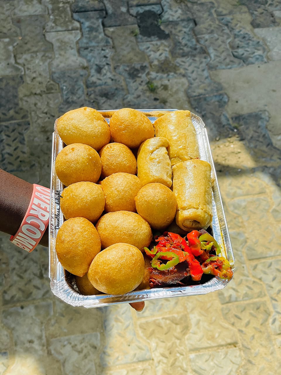 Foil tray of golden puff-puff, spring rolls and peppered fish