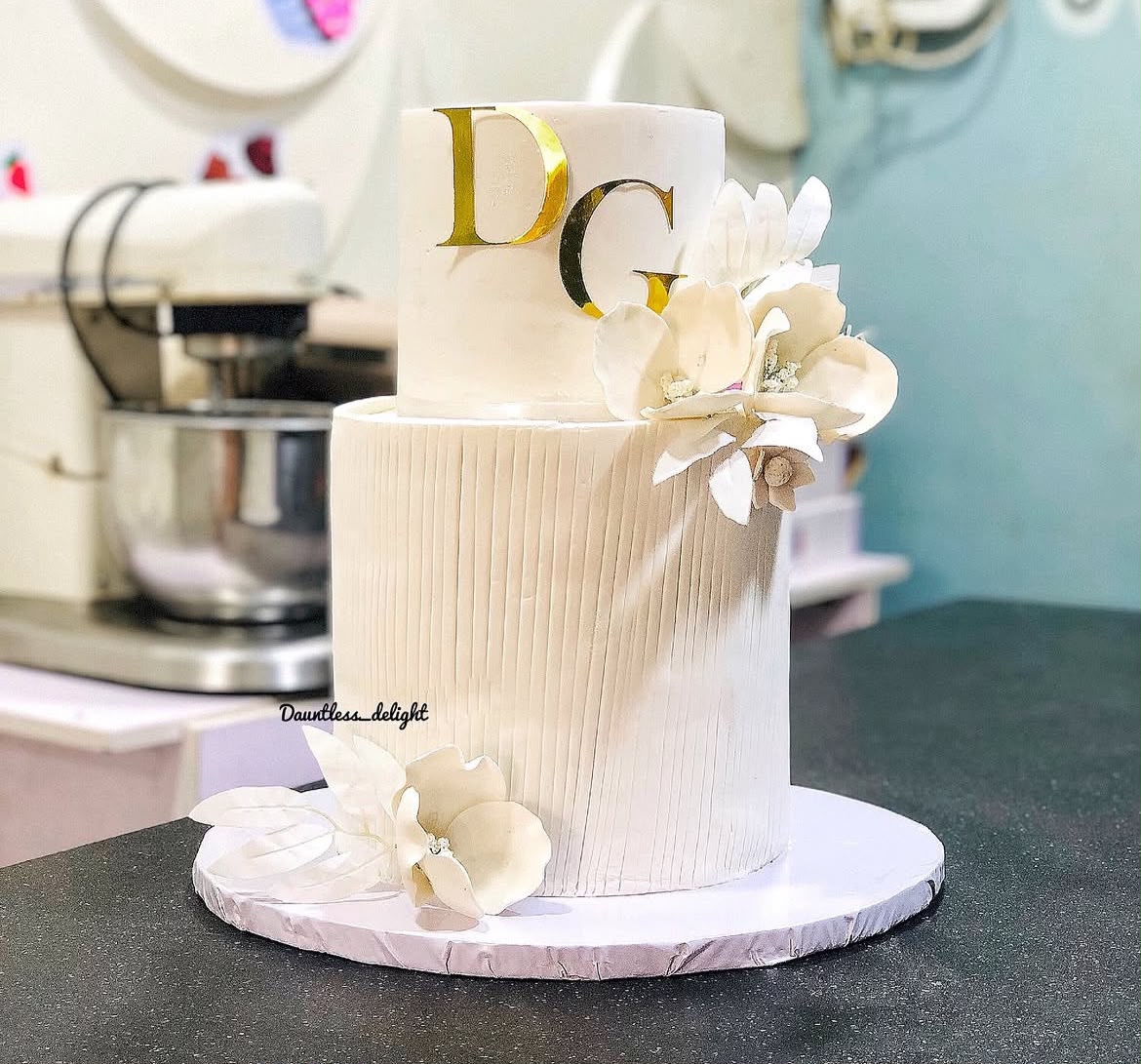 Two tier white wedding cake with gold DG monogram and sugar flowers