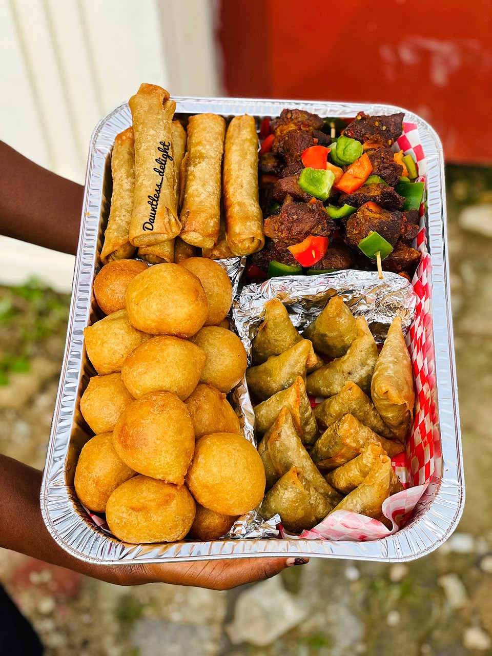 Small chops tray with spring rolls, samosas, puff-puff and peppered beef skewers